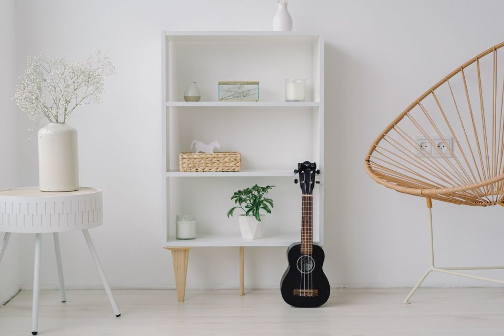 A modern minimalist living room setup featuring a ukelele, shelves, and stylish decor.